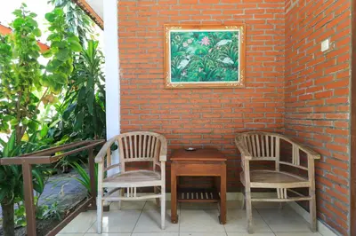 two chairs and a table with a picture on a brick wall at Ayu Lili Garden Hotel Kuta in Kuta