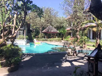 a swimming pool in a yard with a playground at Sari Bali Resort in Kuta