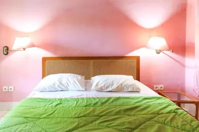 a bedroom with a green bed with two pillows at Sari Bali Resort in Kuta