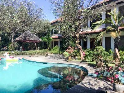 a swimming pool in front of a house at Sari Bali Resort in Kuta
