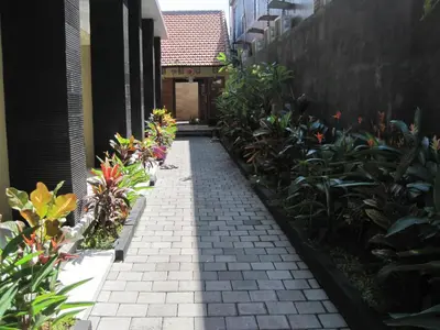 a brick walkway with plants in front of a building at Guest house KupuKupu39 in Kuta