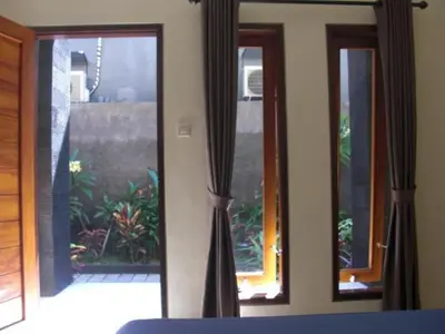 a room with two windows and a view of a patio at Guest house KupuKupu39 in Kuta