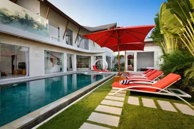 a pool with chairs and an umbrella next to a house at Villa Miro - Luxury, 3 Bed, Central Seminyak in Seminyak