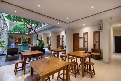 a restaurant with wooden tables and chairs and a pool at Angkul Angkul Segara Beach Kuta by Kamara in Kuta