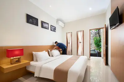 a man putting pillows on a bed in a hotel room at Angkul Angkul Segara Beach Kuta by Kamara in Kuta