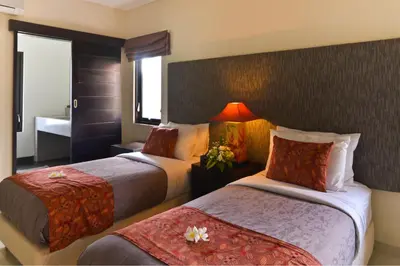 a hotel room with two beds and a bathroom at Elok Villas in Seminyak
