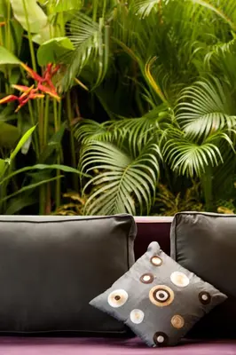 a couch with two pillows in front of a plant at Elok Villas in Seminyak
