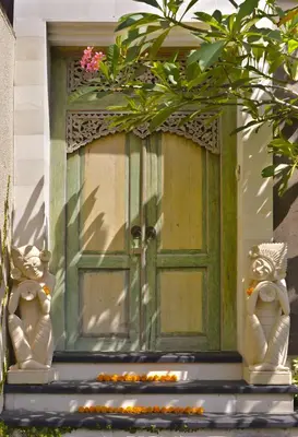 a green door on a building with a plant at Elok Villas in Seminyak
