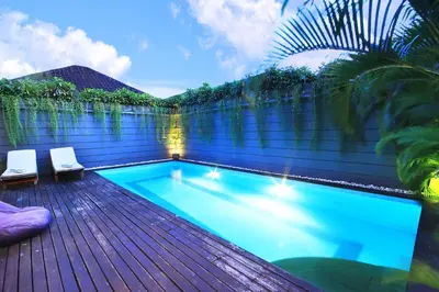 a swimming pool on a wooden deck with two chairs at Letos Kubu Homestay in Kuta