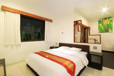 a bedroom with a large white bed with a window at Letos Kubu Homestay in Kuta
