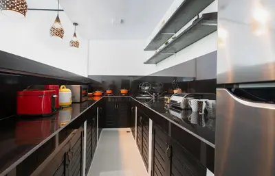 a large kitchen with black counters and stainless steel appliances at Aurora Villa, Seminyak in Seminyak