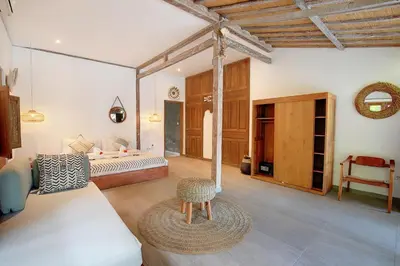 a bedroom with a bed and a chair in a room at Villa Balimasan 10 mins to Canggu in Seminyak