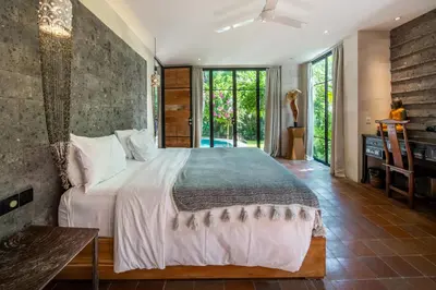 a bedroom with a large bed and a table at Villa River Garden Canggu in Kerobokan