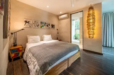 a bedroom with a large bed and a chandelier at Villa River Garden Canggu in Kerobokan