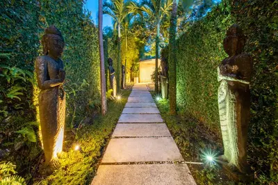 a path in a garden with two statues on it at Villa River Garden Canggu in Kerobokan