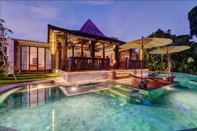 a house with a swimming pool and a house with umbrellas at Villa River Garden Canggu in Kerobokan