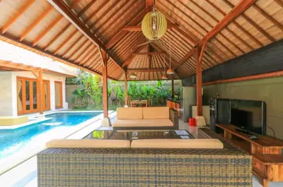 an outdoor living room with a pool and a pavilion at Three Brothers Bali Legian Bungalows & Villas in Legian