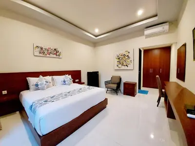 a bedroom with a bed and a desk in a room at The New Moon Seminyak in Seminyak