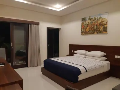 a bedroom with a bed and a painting on the wall at The New Moon Seminyak in Seminyak