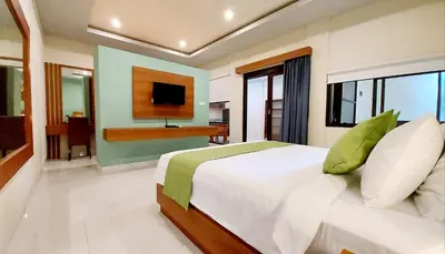 a bedroom with a large bed and a television at The New Moon Seminyak in Seminyak