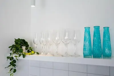 a row of wine glasses and blue vases on a shelf at Villa Opihr in Seminyak