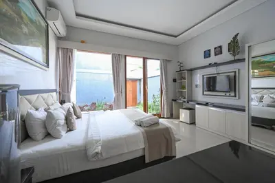 a bedroom with a large bed and a television at Hoki Villa by Urbanview Villa in Kerobokan