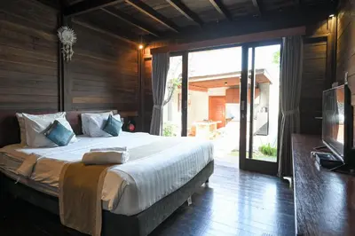 a bedroom with a large bed and a sliding glass door at Hoki Villa by Urbanview Villa in Kerobokan