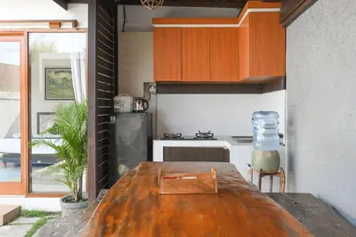 a kitchen with a wooden table and a stove at Hoki Villa by Urbanview Villa in Kerobokan