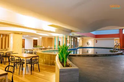 a hotel with a pool and tables and chairs at Siesta Legian in Legian
