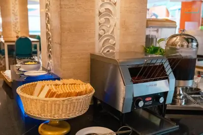 a coffee maker and a basket of bread on a counter at Siesta Legian in Legian