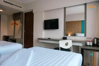 a hotel room with two beds and a desk and a tv at Siesta Legian in Legian