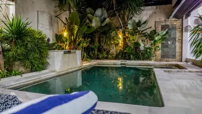 a swimming pool in the middle of a garden at Ahimsa Moon Villa Seminyak in Seminyak