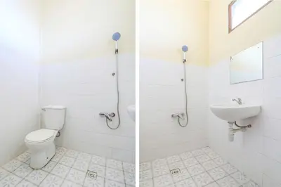 a white bathroom with a toilet and a sink at Hotel O Nan Berlian Inn in Legian