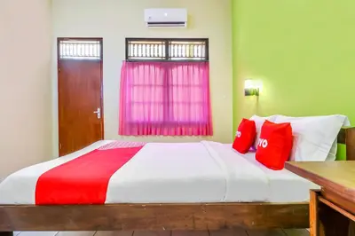 a bedroom with a bed with red and white pillows at Hotel O Nan Berlian Inn in Legian