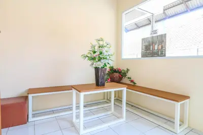 a vase of flowers on a table in a waiting room at Hotel O Nan Berlian Inn in Legian