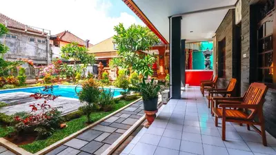 a patio with chairs and a swimming pool at Mia Guest House in Legian