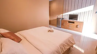 a hotel room with a bed and a television at Mia Guest House in Legian