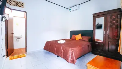 a bedroom with a bed and a bathroom with a toilet at Mia Guest House in Legian