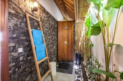 a bathroom with a wooden ladder in a brick wall at Villa Katapappa in Seminyak