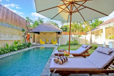 a pool with two lounge chairs and an umbrella at UMA LIMA VILLA - 7Min Beach Access - 10min to Canggu in Canggu