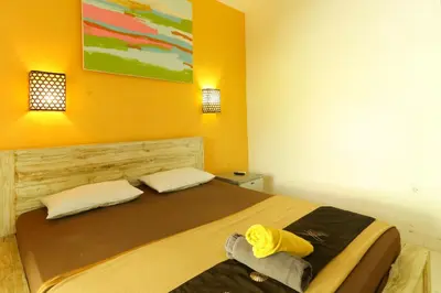 a bedroom with a bed with a yellow wall at The Legian Mas Beach Inn in Kuta