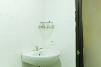 a bathroom with a sink and a basket on the wall at The Legian Mas Beach Inn in Kuta