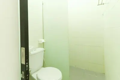 a white bathroom with a toilet and a shower at The Legian Mas Beach Inn in Kuta