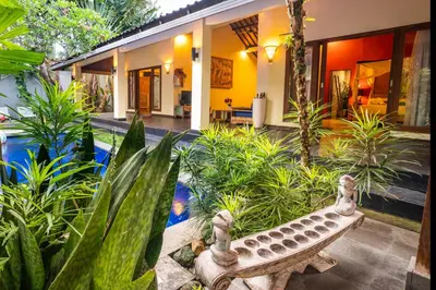 a garden with a stone bench in front of a house at Villa Agni - BEST location! 3BR villa at the heart of Seminyak in Seminyak