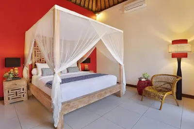 a bedroom with a canopy bed and a chair at Villa Agni - BEST location! 3BR villa at the heart of Seminyak in Seminyak