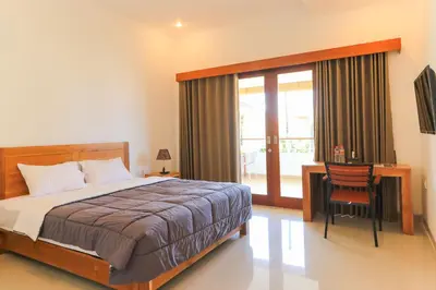 a bedroom with a bed and a desk and a window at Manu Guest House 2 in Canggu