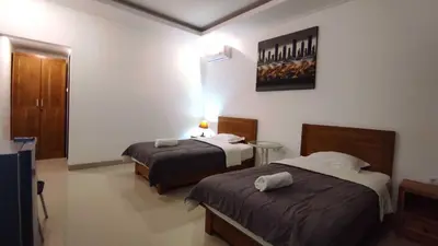 a hotel room with two beds and a tv at Manu Guest House 2 in Canggu