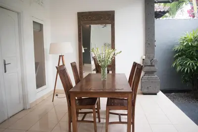 a dining room table with chairs and a vase of flowers at Premium Villas Seminyak I in Seminyak