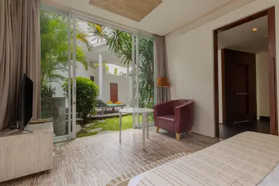 a bedroom with a bed and a chair and a television at Taman Mesari Luxury Villas-Seminyak in Seminyak