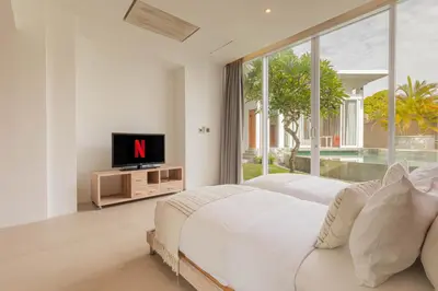 a white bedroom with two beds and a tv at Taman Mesari Luxury Villas-Seminyak in Seminyak